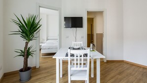 A room with a white table, a potted plant, a bed, and a TV mounted on the wall. - The apartment is located in a stunning location, almost impossible to find! You are in the authentic heart of Milan, between Sant'Ambrogio district, renowned above all for the church of Santa Maria delle Grazie and the Catholic University and the charm o (Milano)