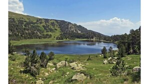 A serene landscape with a lake, rolling hills, and scattered trees. - Bel Appartement Dans un Chalet vue sur le lac (Les Angles)