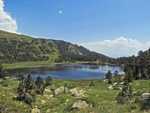 Un lago rodeado de colinas verdes y rocas dispersas.