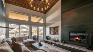 A modern living room with a fireplace, large windows, and a cozy seating area.