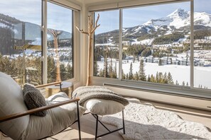 Una habitación con un ventanal que ofrece vistas a un paisaje nevado de montaña.