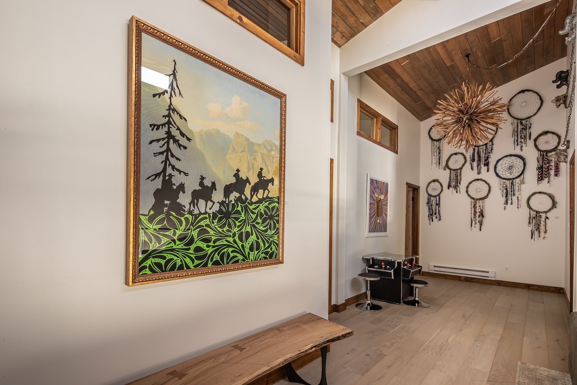 Passadís amb terres de fusta, una banca i obres d'art, incloent un quadre emmarcat d'una escena de muntanya i penjalls.