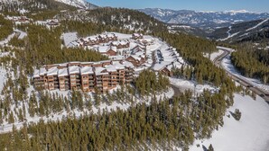 A ski resort with multiple lodges, a winding road, and snow-covered mountains in the background.
