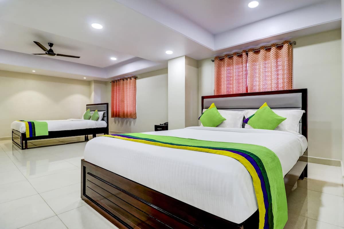 A hotel room with two beds, a ceiling fan, and a window with patterned curtains.