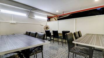 A conference room with a long table, several chairs, a fan, and a whiteboard.