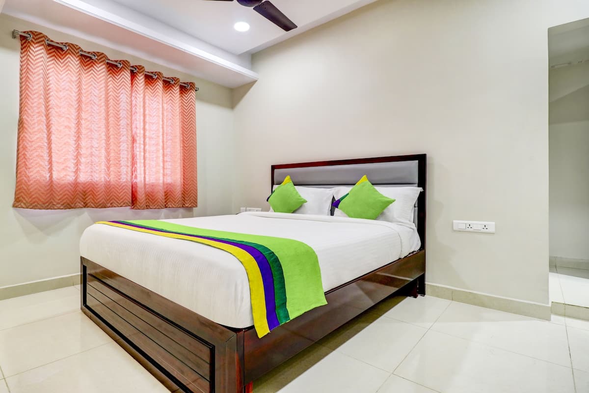 A neatly made bed with a wooden headboard, white bedding, and colorful pillows.