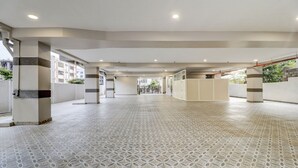 A spacious corridor with patterned flooring, columns with decorative bands, and a view of the outside through a gated entrance. - Treebo Grand Milan (Visakhapatnam)