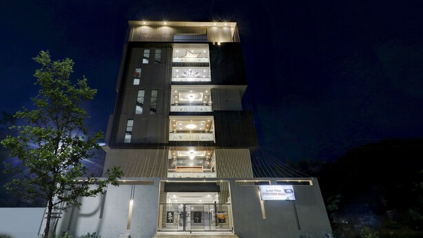 A multi-story building with illuminated windows and a sign indicating a function hall. - Treebo Grand Milan (Visakhapatnam)