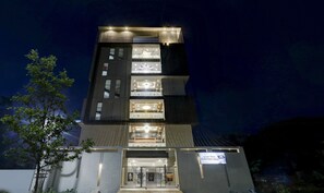A multi-story building with illuminated windows and a sign indicating a function hall. - Treebo Grand Milan (Visakhapatnam)