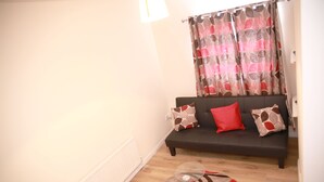A living room with a sofa, patterned cushions, and a patterned curtain. - Canning Town Cozy one Bedroom Apartment (London)