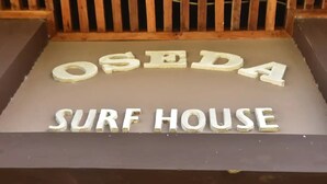 Un letrero con las palabras 'OSEDA SURF HOUSE' en letras blancas sobre un fondo oscuro.