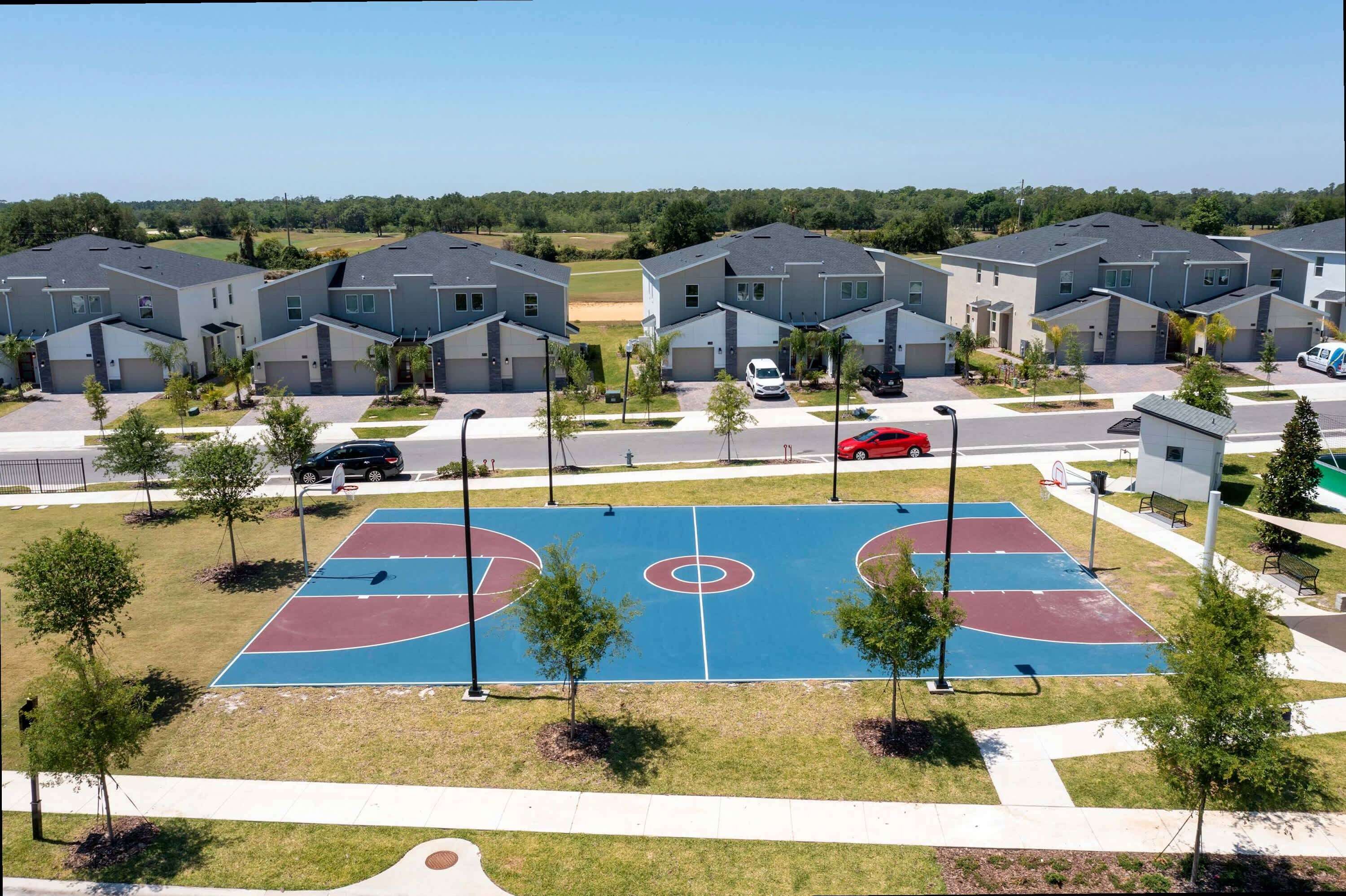 A residential area with modern houses, a basketball court, and a parking area.