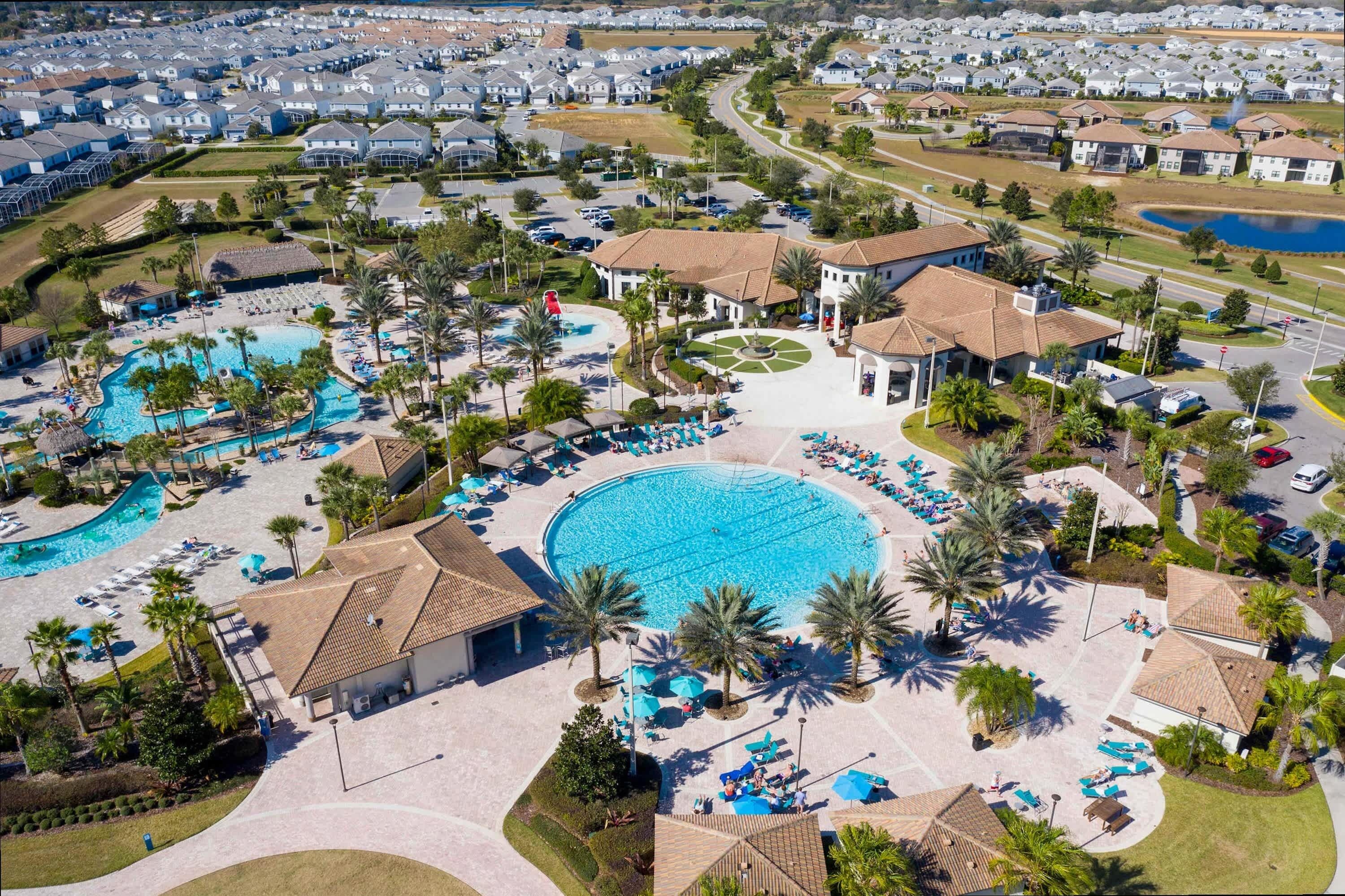 Eine Vogelperspektive zeigt ein Resort mit mehreren Schwimmbecken, Palmen und einer gepflegten Landschaft.