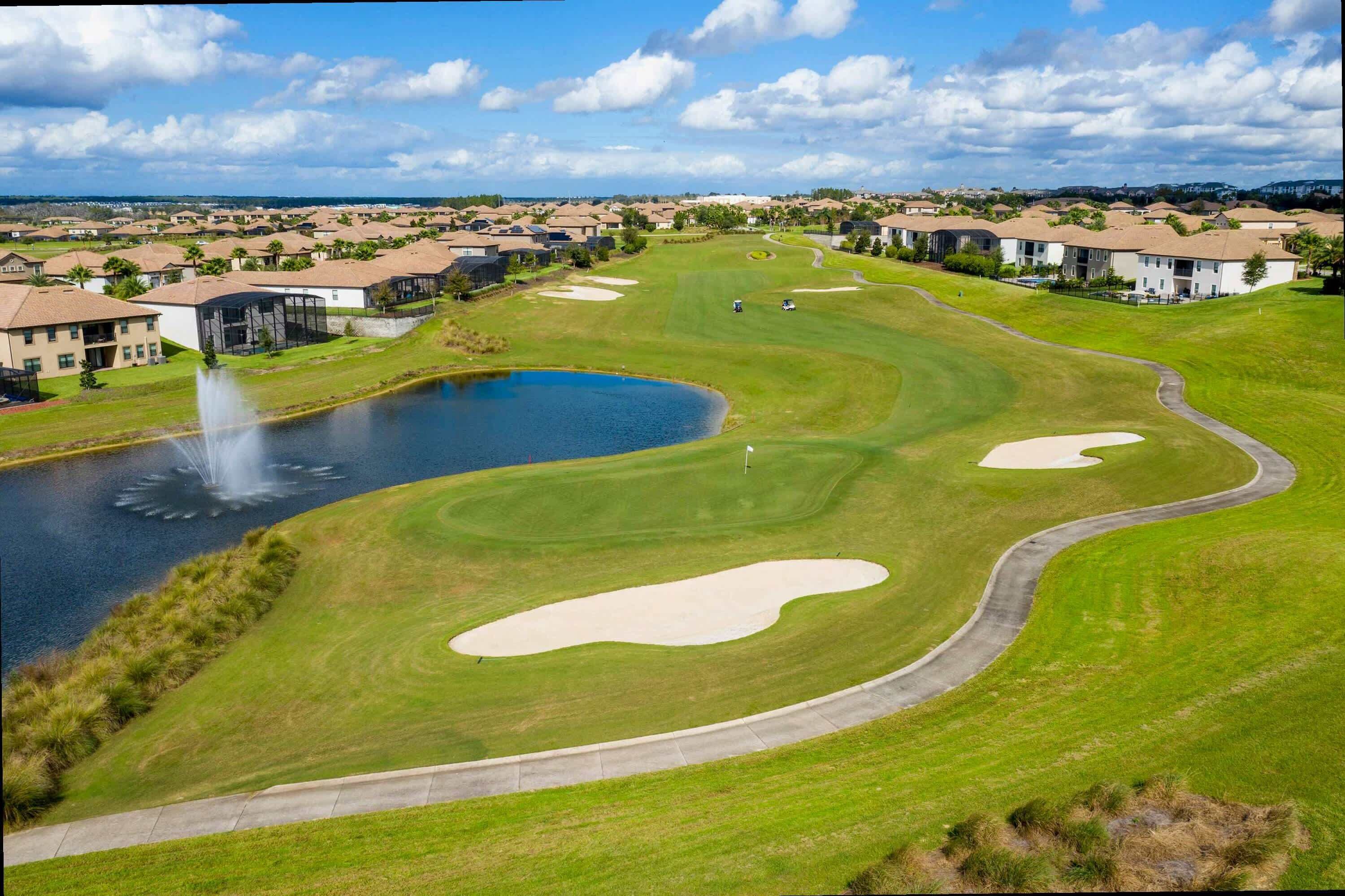 A golf course with bunkers, a pond, and a fountain.
