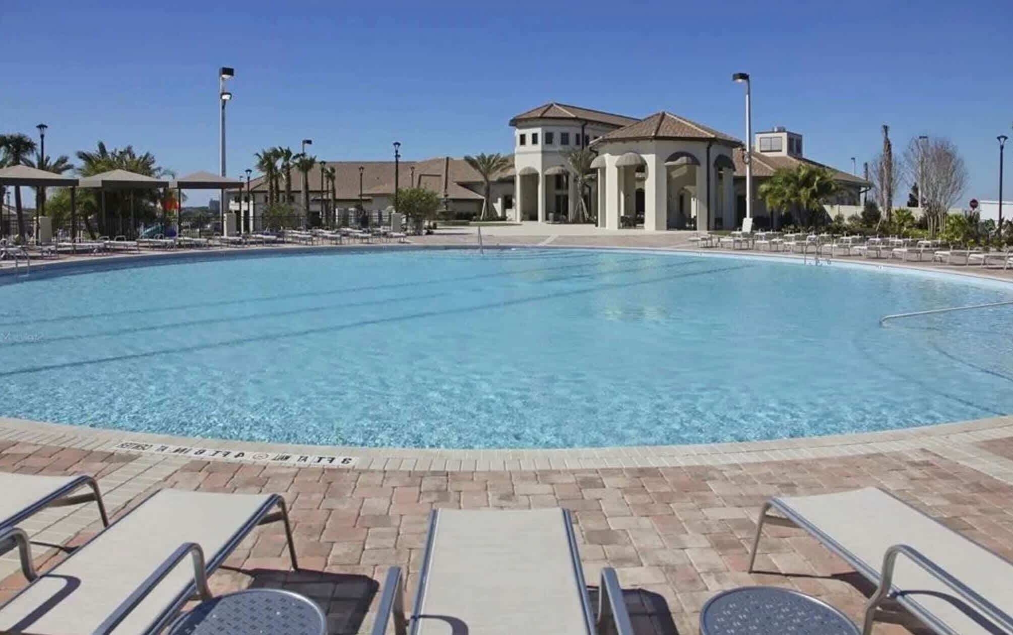 A swimming pool with lounge chairs and a building in the background.