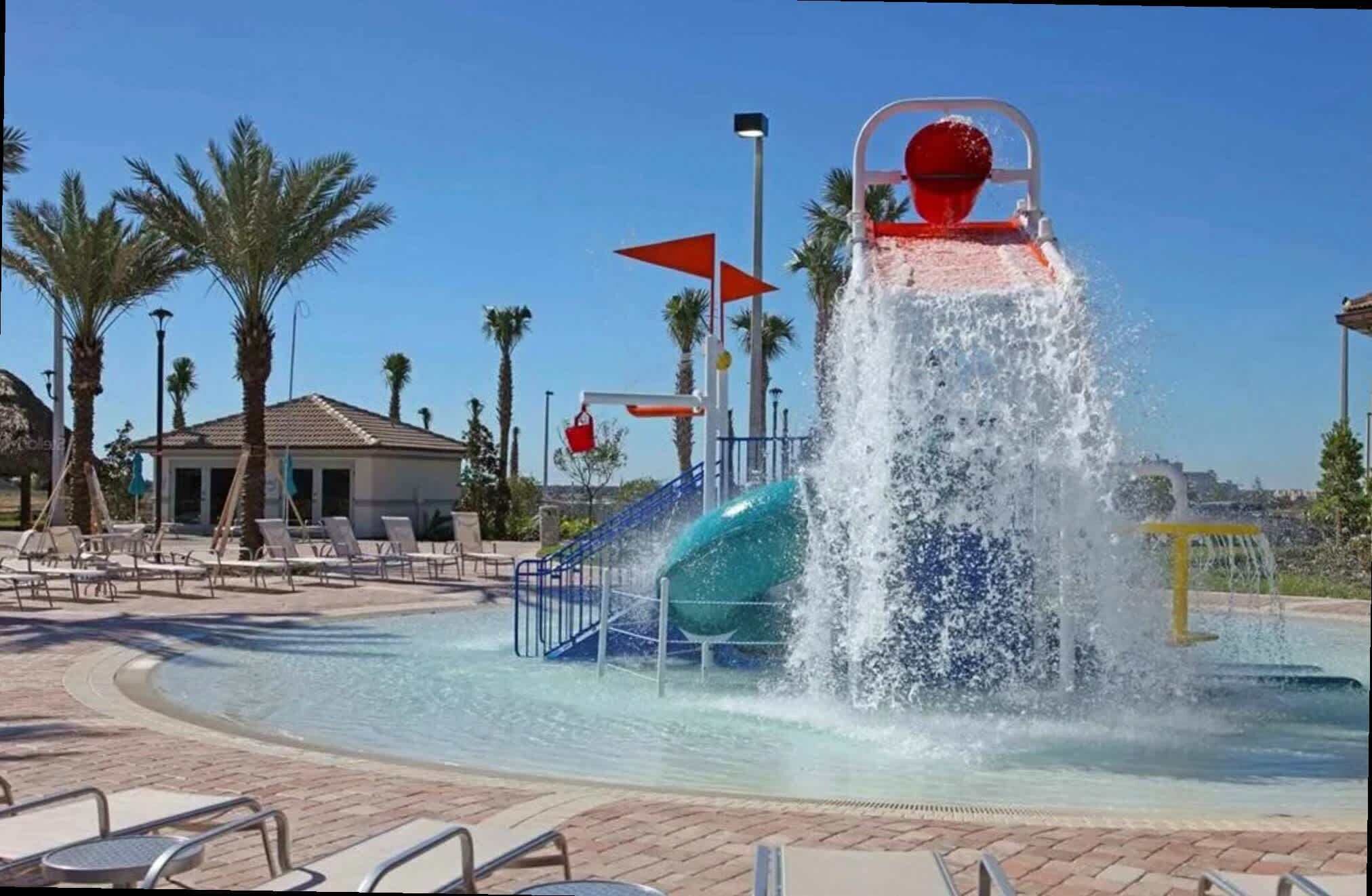 A water park with a water slide, lounge chairs, and a pool.