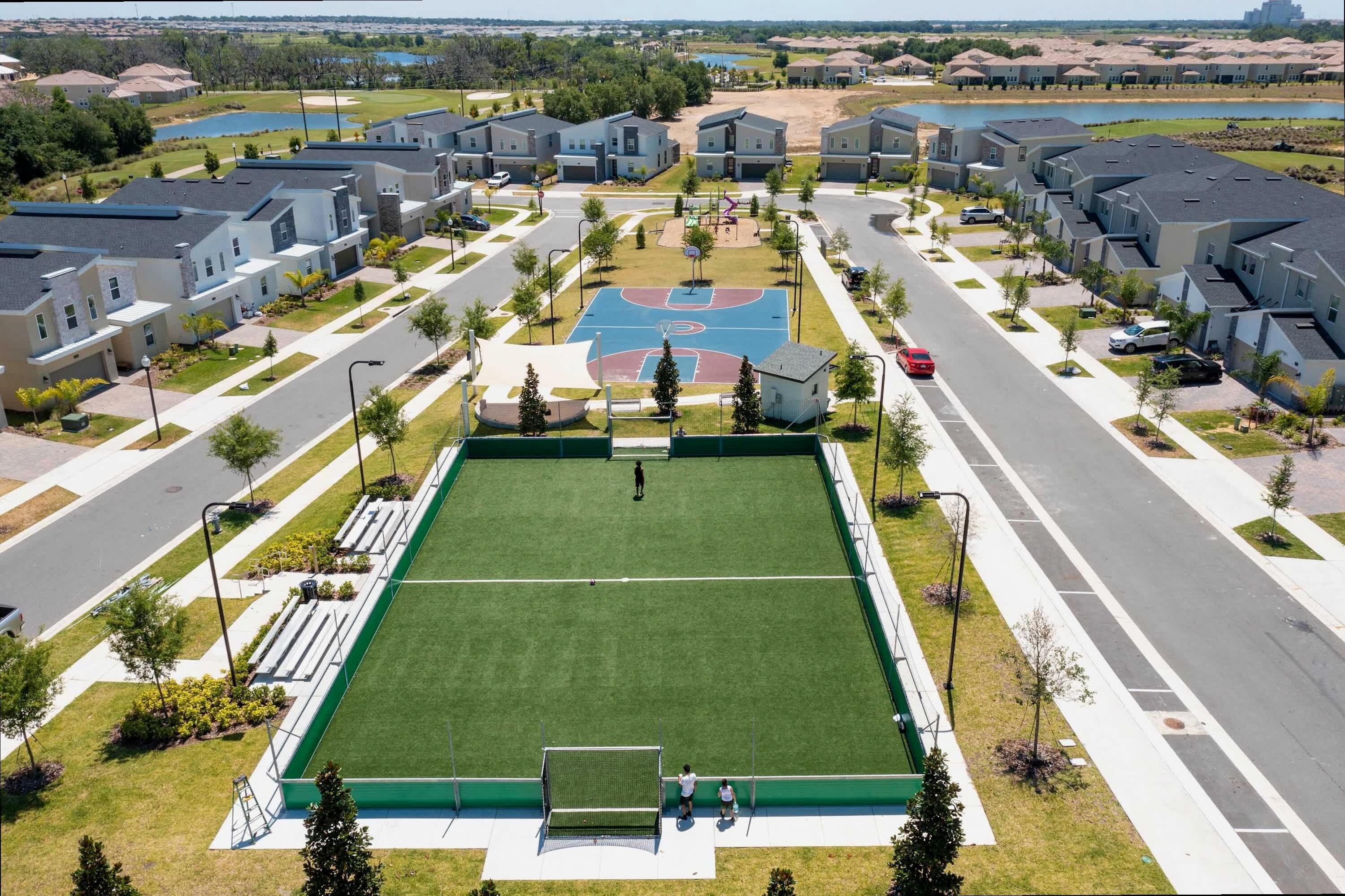 A residential area with modern houses, a basketball court, and a road.