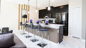 Una cocina moderna con una isla central, electrodomésticos de acero inoxidable y una zona de bar con taburetes.