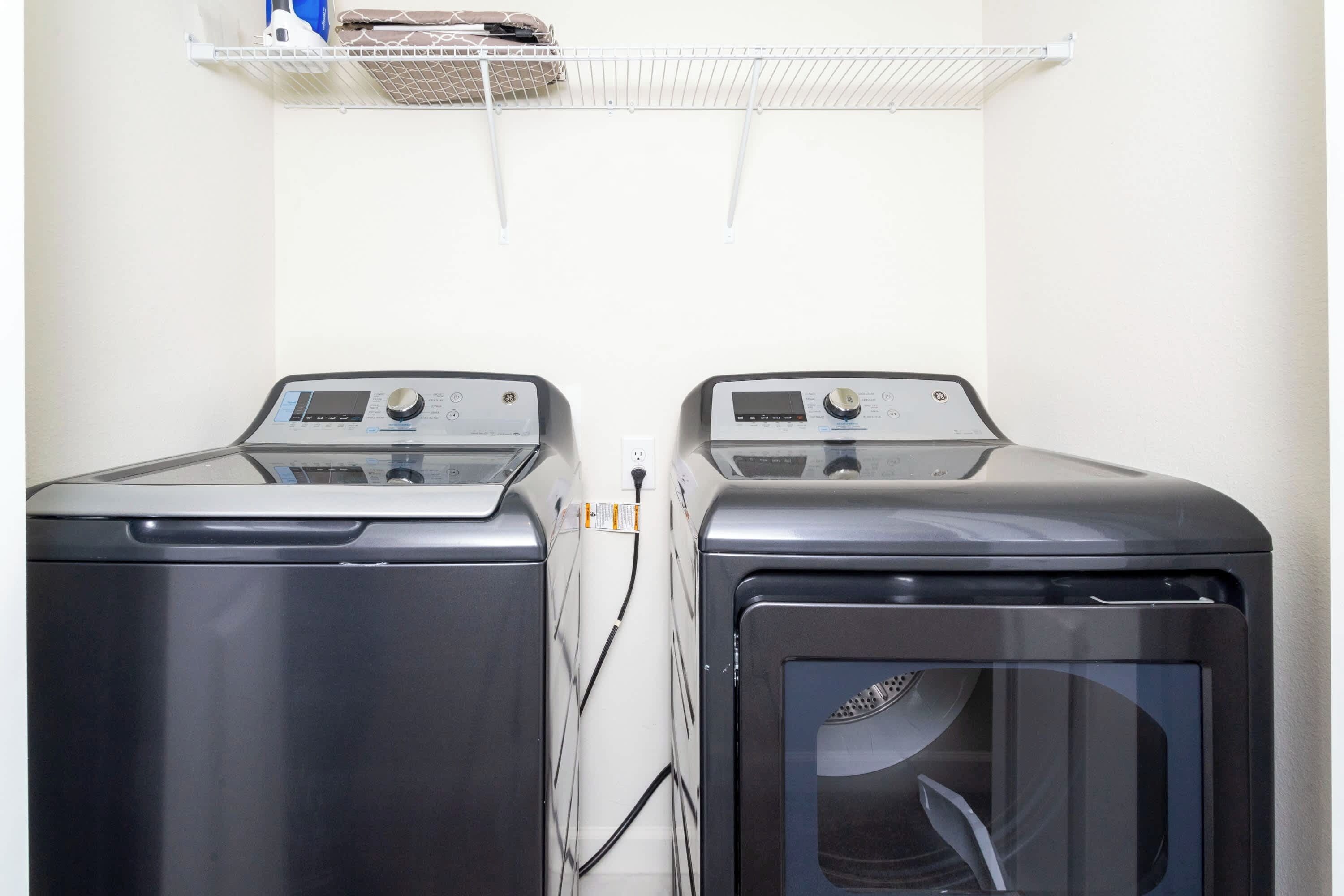 Deux machines à laver à chargement frontal, placées côte à côte, avec une étagère blanche au-dessus.