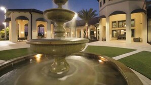 A fountain in a courtyard with a building in the background.
