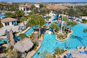 A resort with multiple swimming pools, palm trees, and lounge areas. - Gorgeous 4Bd w/ Pool @ Champions Gate 1196 (Davenport)
