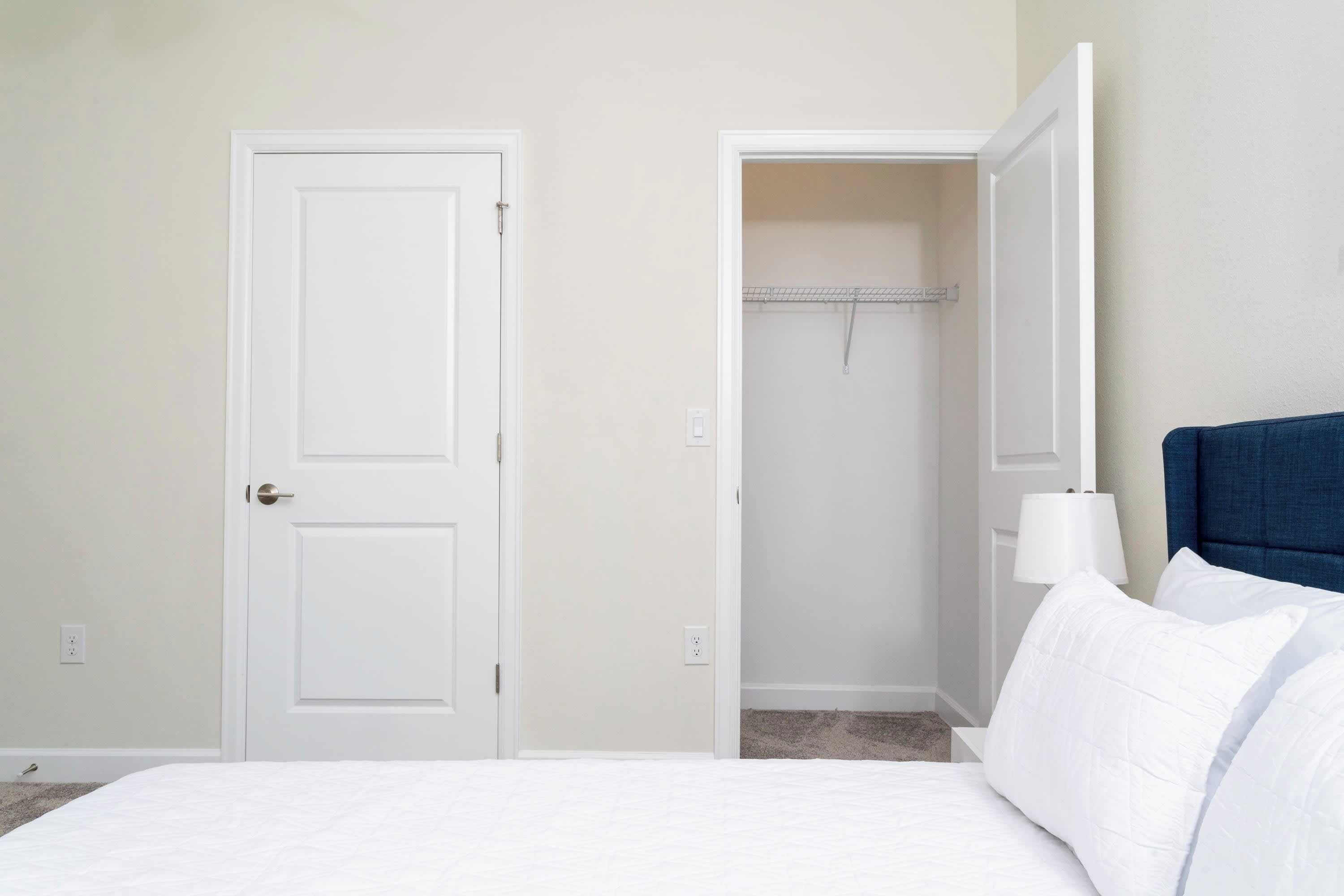 A bedroom with a bed, a wardrobe, and a nightstand with a lamp.