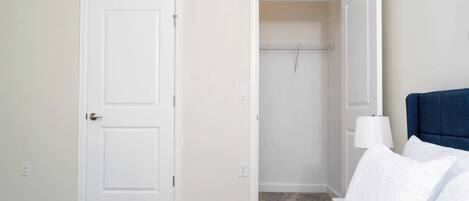 A bedroom with a bed, a wardrobe, and a nightstand with a lamp.