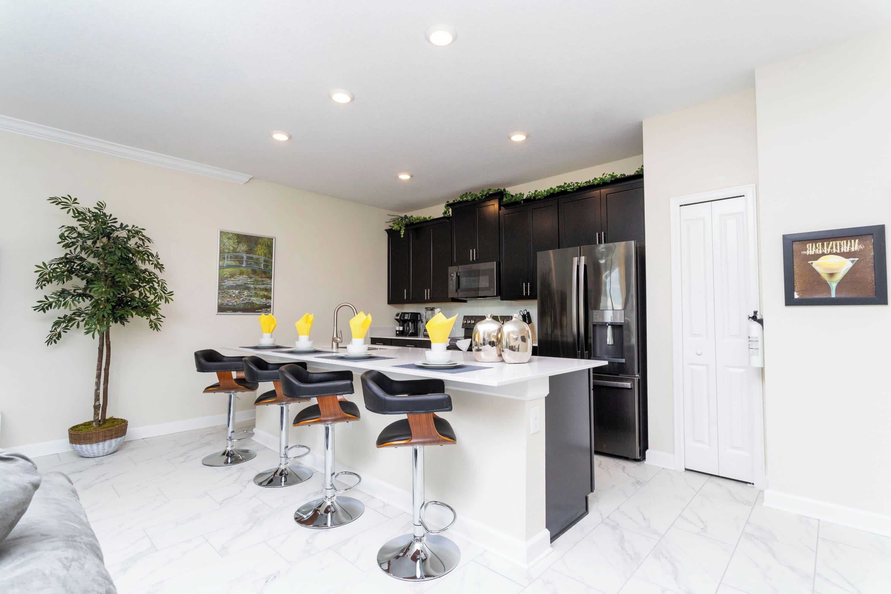 A modern kitchen with dark cabinets, stainless steel appliances, and a white island with bar stools.