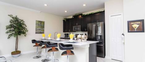 A modern kitchen with dark cabinets, stainless steel appliances, and a white island with bar stools.