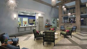 A spacious lobby with a reception desk, multiple seating areas, and decorative wall art.