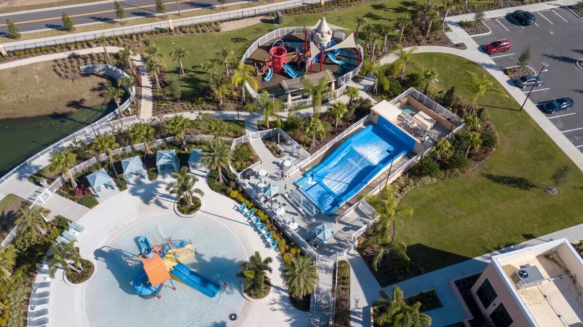 An aerial view of a resort with a large pool, water slides, and a beach area.