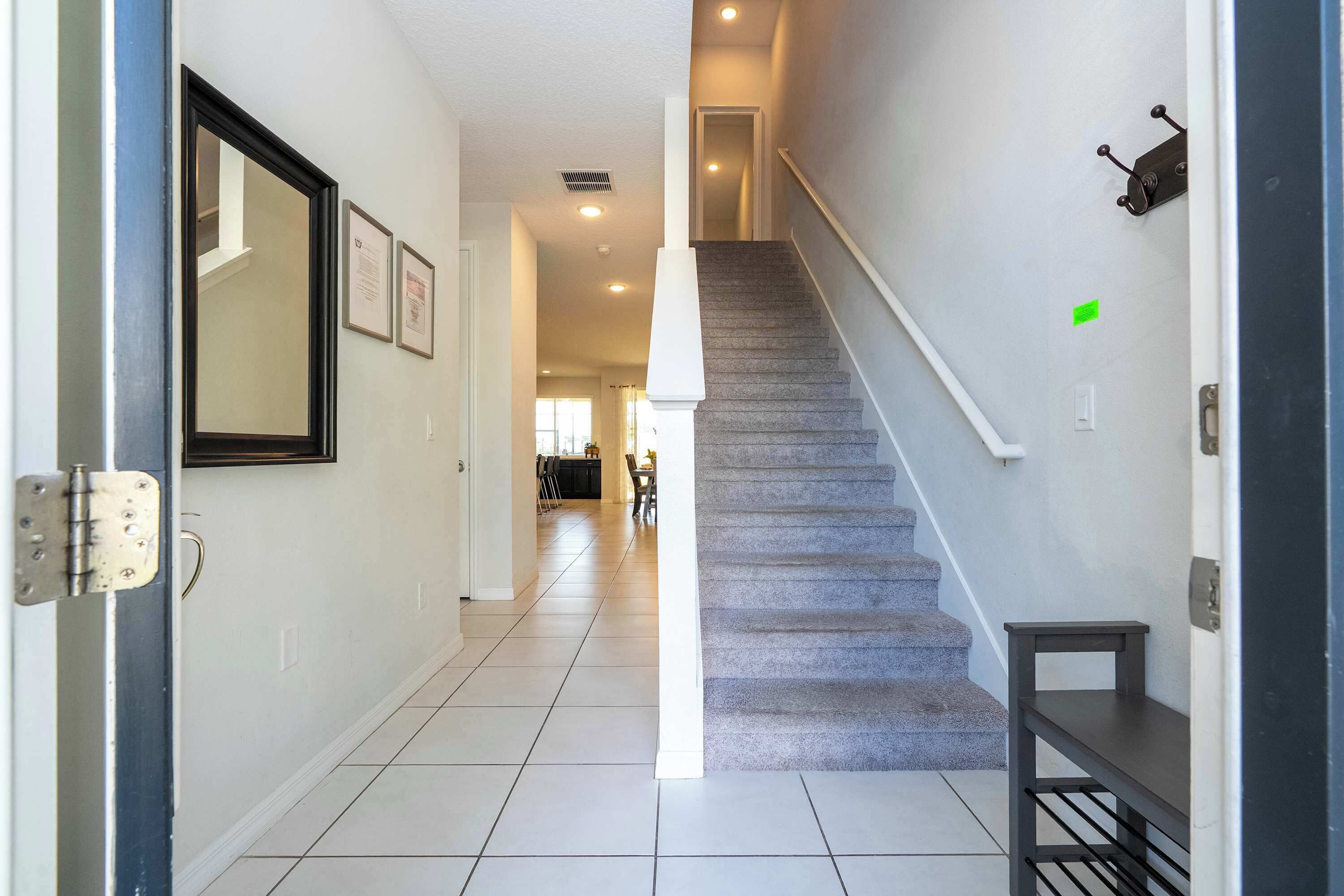 A hallway with a carpeted staircase, a door with a handle, and a wall-mounted shelf.