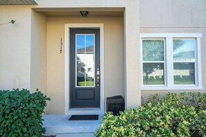 A front door with a mailbox, a small trash bin, and a window to the right.