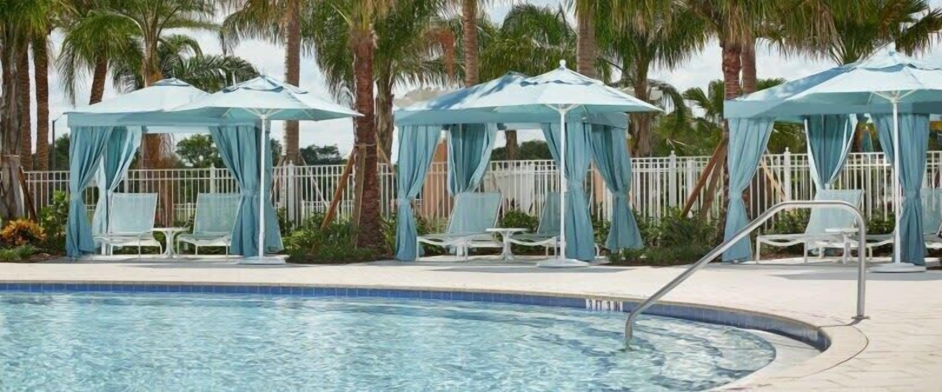 A pool area with blue canopies and white lounge chairs.