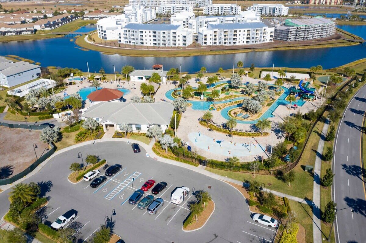 An aerial view of a hotel complex with a swimming pool, parking lot, and a lake.