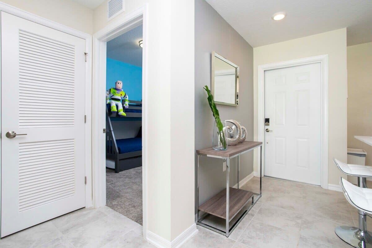 A hallway with a white door, a console table with a vase and a mirror, and a blue room in the background.