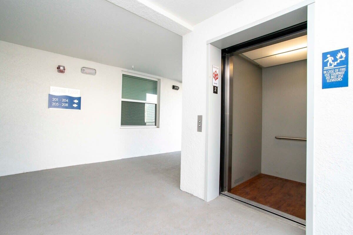 A hallway with directional signs to rooms 201-204 and 205-208, an elevator, and a fire safety sign.