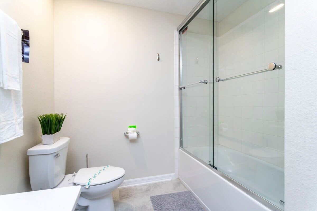 Une petite salle de bain comprenant des toilettes, une douche en verre et une petite plante en pot.