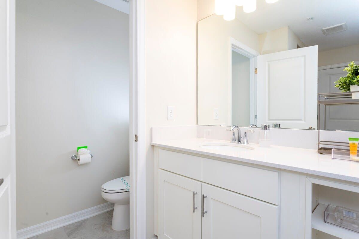 A modern bathroom with a white sink, mirror, and cabinets.