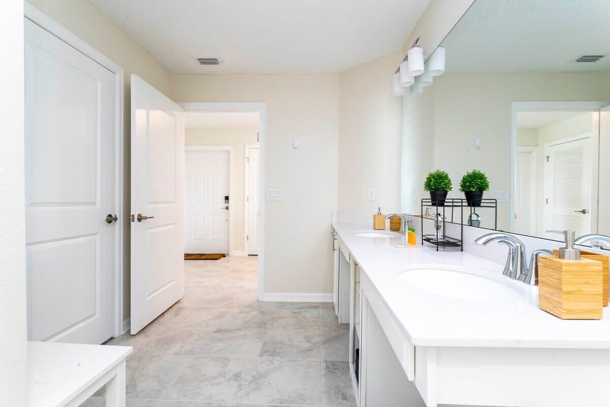 Une salle de bain moderne avec un double vasque, des meubles blancs et un grand miroir.