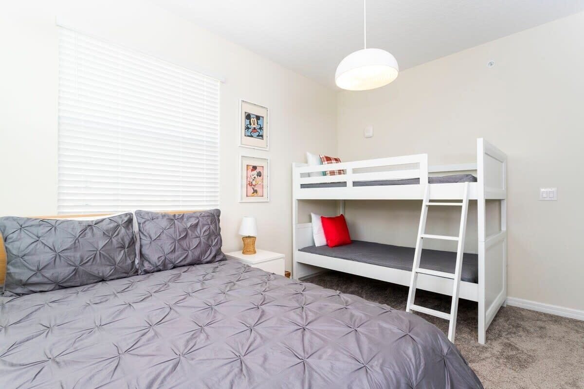 A bedroom with a bed, bunk bed, and a bedside table with a lamp.