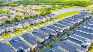 Zona residencial con casas modernas, una extensa masa de agua y un parque arbolado.