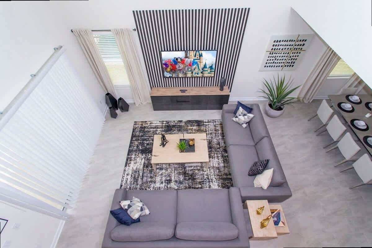 Una sala moderna con un televisor grande, un sofá gris y una mesa de centro.