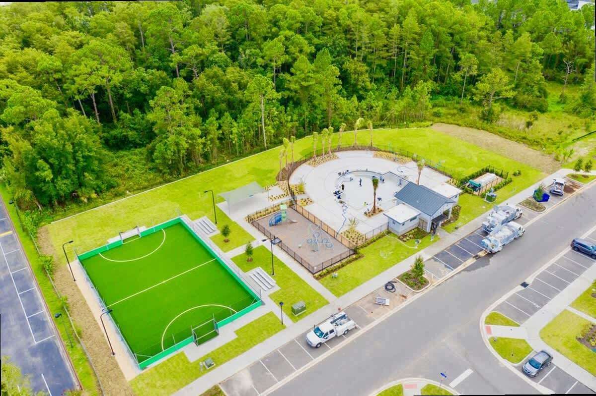 Vista aérea de un complejo deportivo con un campo de fútbol, un edificio circular y zonas de estacionamiento.