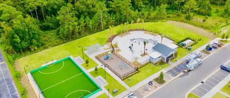Vista aérea de un complejo deportivo con un campo de fútbol, un edificio circular y zonas de estacionamiento.