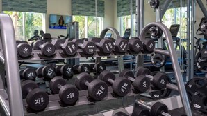 Une salle de sport équipée de divers appareils de musculation, notamment des haltères et des barres.