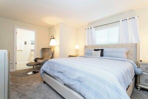 Ein Schlafzimmer mit Bett, Sessel, Nachttisch und Lampe.
