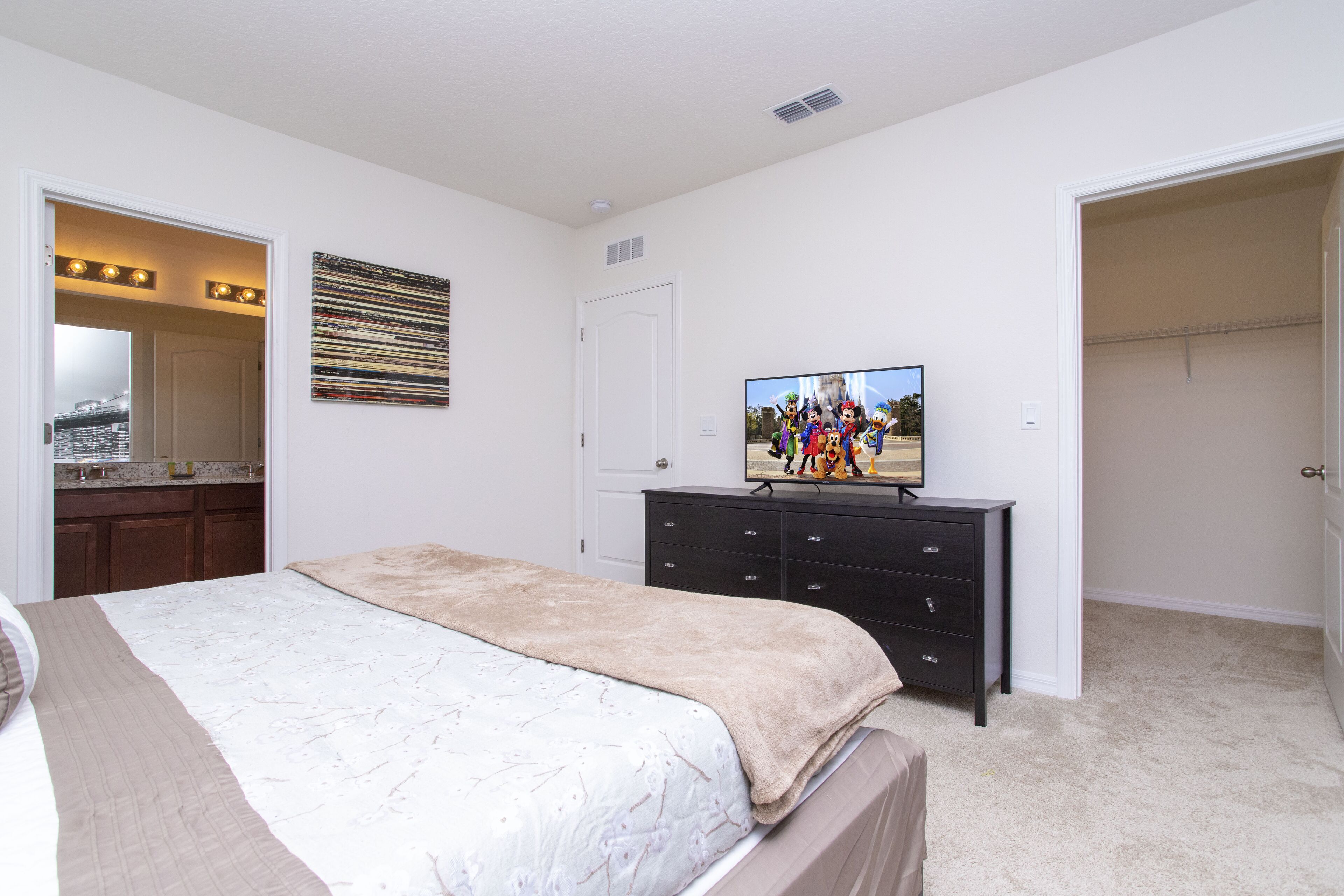 Ein Schlafzimmer mit Bett, Kommode, Fernseher und Kleiderschrank.