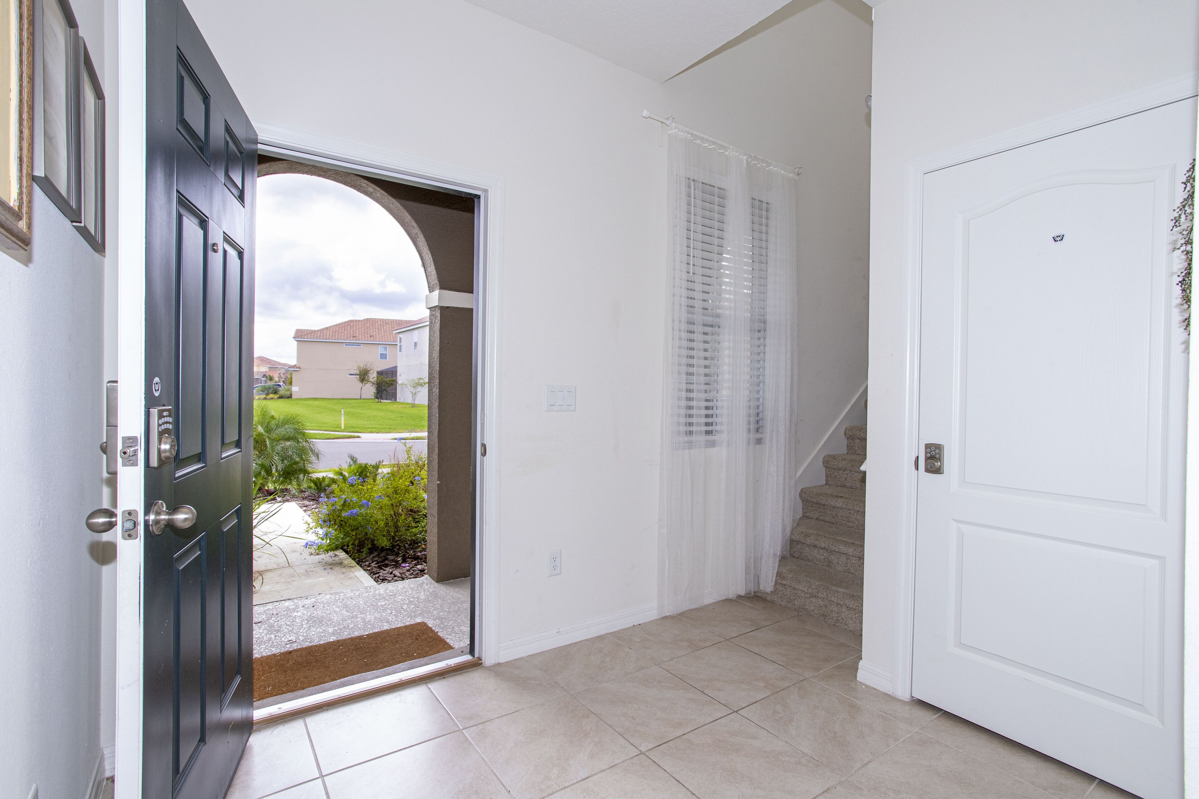 A hallway with a dark door, a white door, and a staircase leading to an outdoor area.