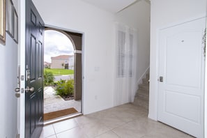 A hallway with a dark door, a white door, and a staircase leading to an outdoor area.